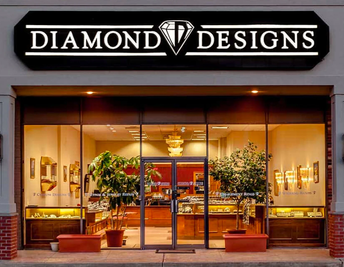 A storefront with a black sign that reads "DIAMOND DESIGNS" with a diamond graphic. The store window displays jewelry and engagement rings.